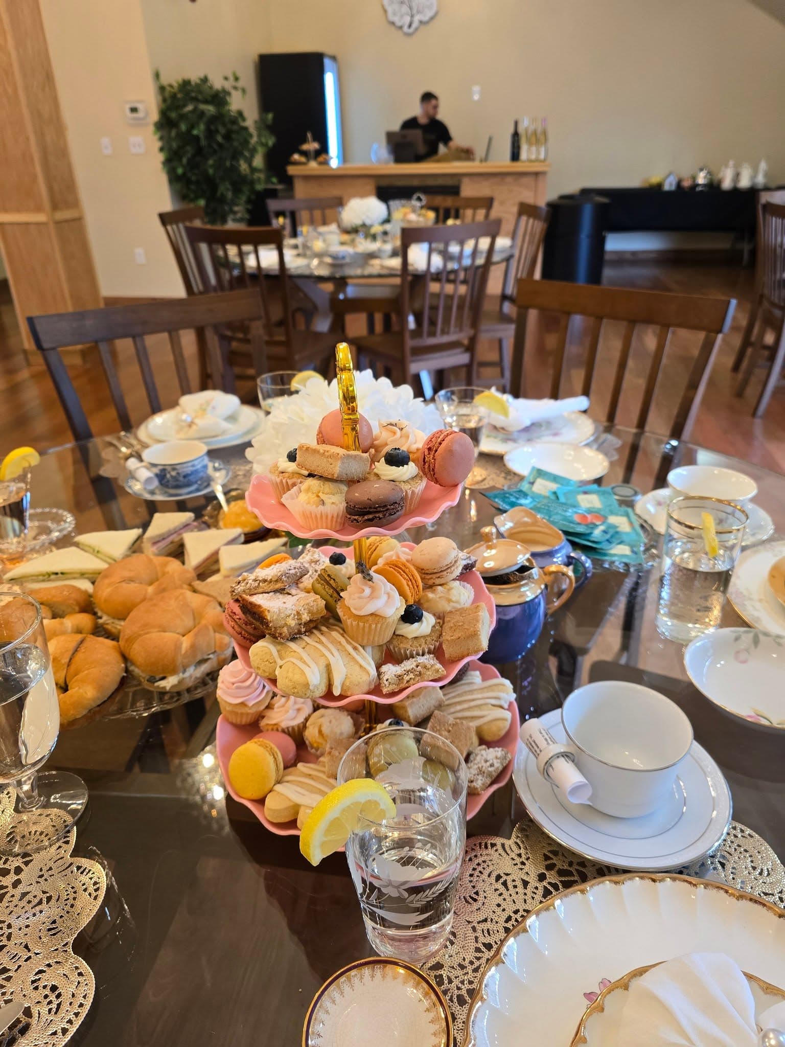 Kay & Rose tea-party table with a pink tiered dessert stand, croissant sandwiches, china teacups, and lemon water