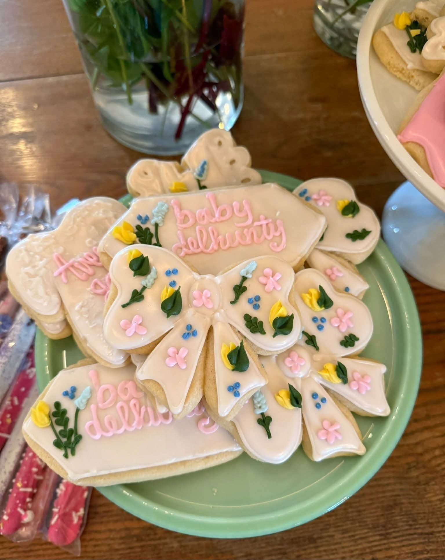 Hand-decorated baby celebration cookies arranged on a green tray